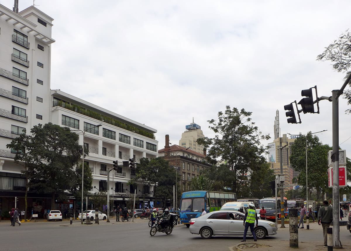 Kenyatta Avenue in Nairobi on a working day: buses, cars and a motorbike at a junction under a grey sky